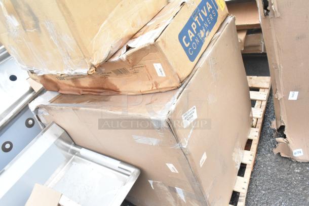 Boxes with "Captiva Containers" label containing scratch and dent items, including sinks, on a pallet. Visible wear on packaging.