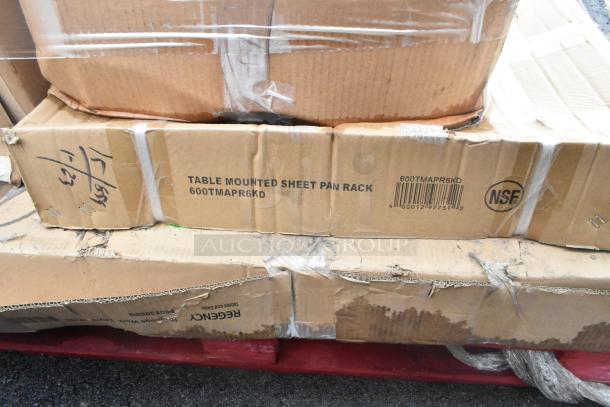 Boxes of new scratch and dent items, including table mounted sheet pan rack model 600TMAPR6KD. Visible wear, marked NSF.