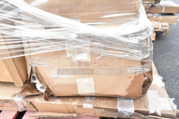 Cardboard box wrapped in plastic containing new scratch and dent items, including pie pans and work table, on a pallet.