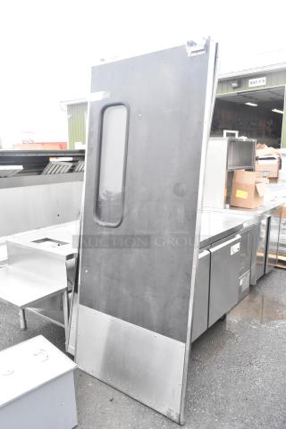 Two swinging kitchen doors with viewing panels and bottom plates, includes hardware, shown outdoors, used condition.