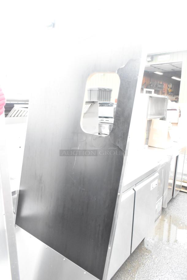 Two swinging kitchen doors with mounting hardware, black surface, visible wear marks, rectangular window cutout.