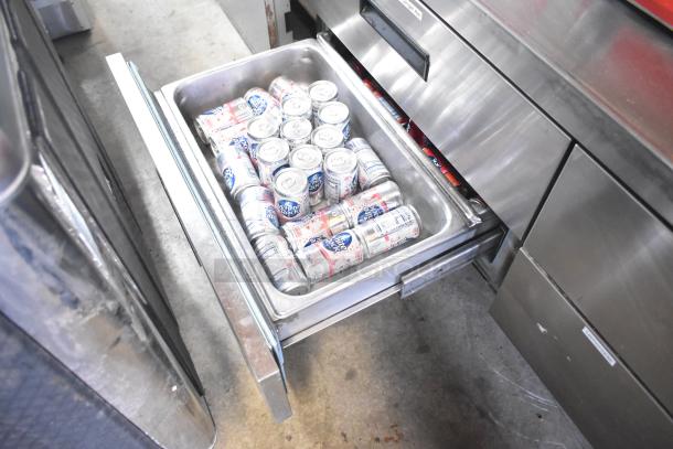 Delfield commercial chef base with four drawers, open drawer showing canned drinks. On commercial casters, 115V, 1 Phase.