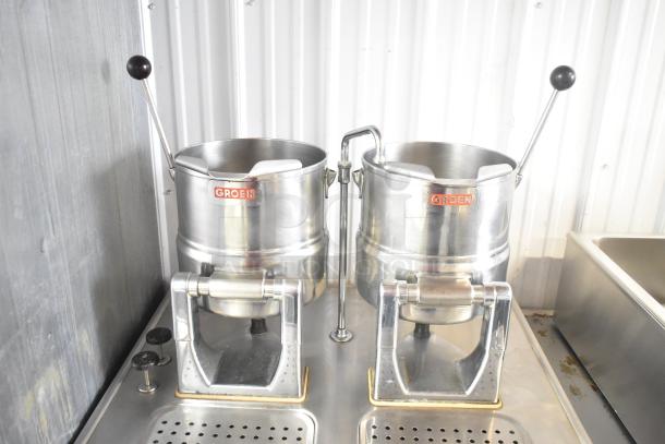 2 Groen tilting kettles on Market Forge MT2-5ES modular base, stainless steel, lever handles, branded logos visible.