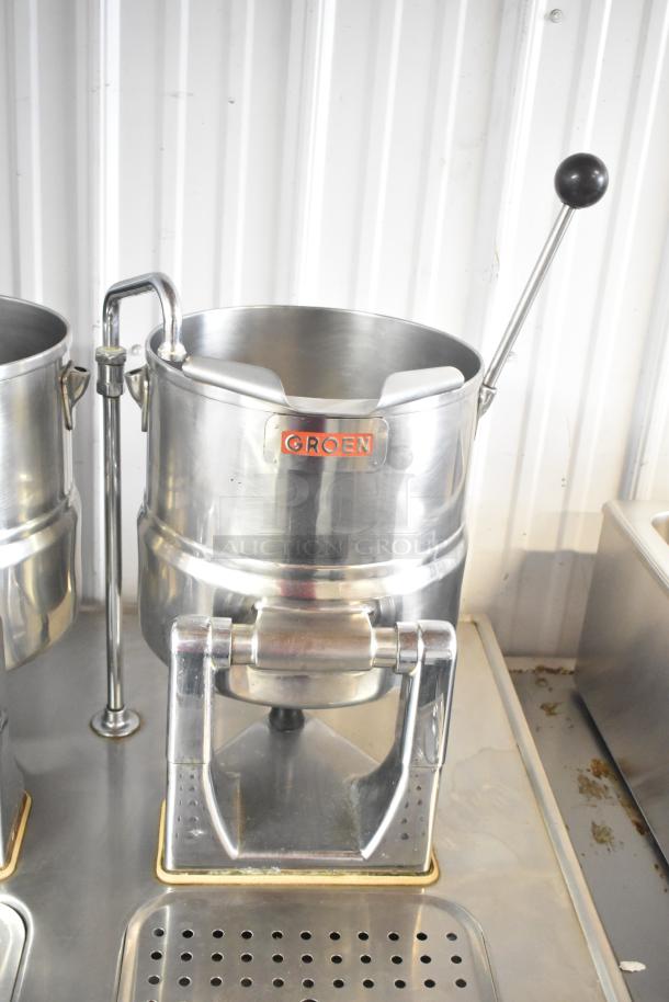 Two stainless steel Groen tilting kettles on Market Forge MT2-5ES modular base, featuring lever handles, in good condition.