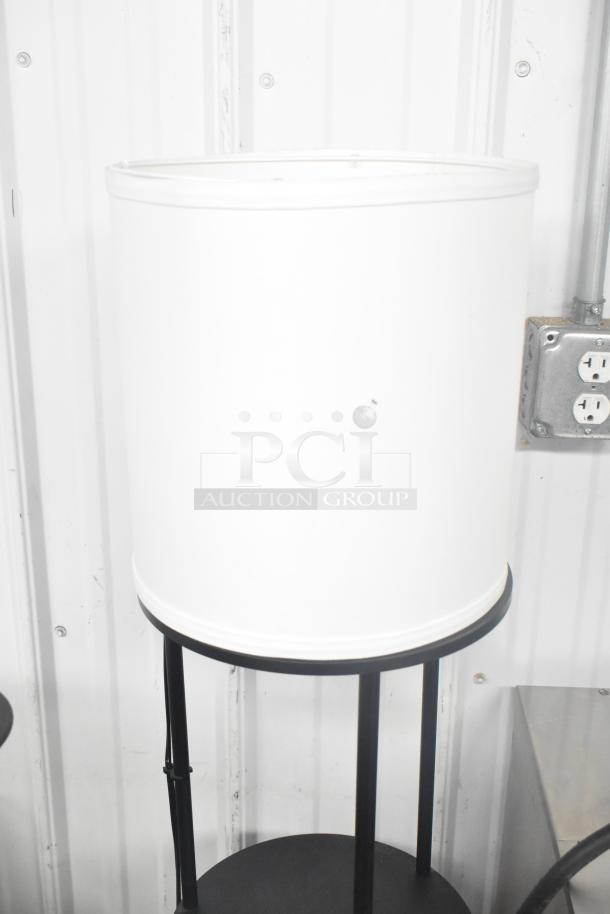 Light fixture with three under shelves, featuring a cylindrical white shade and black metal frame. Ideal for modern decor.