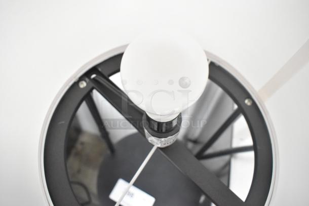 Light fixture with three under shelves, in good condition. Black frame, white bulb, sturdy design, ideal for storage and lighting.