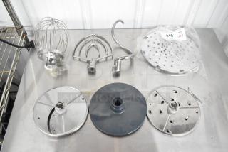 Set of 7 attachments: whisk, paddle, dough hook, 2 processor blades, pelican head grater. Excellent condition. Lot label visible.