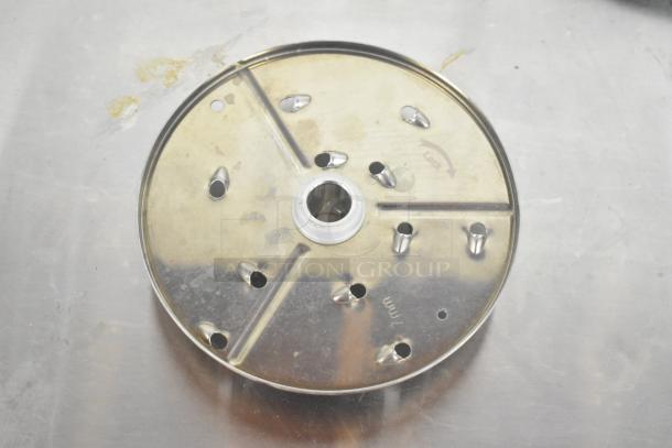 Pelican head grating blade in used condition, showing metal surface with locking text visible. Key for food processor.