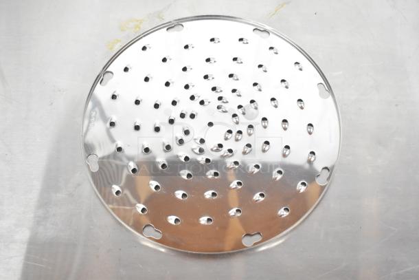 Stainless steel grating blade for food processor, used condition. Includes manufacturer markings around the edge.