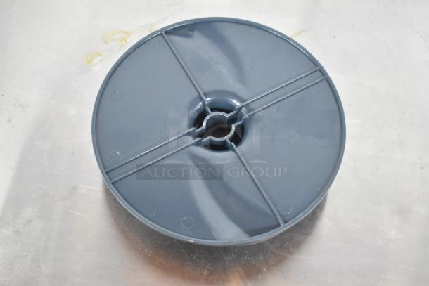 Gray food processor blade attachment, circular, plastic material, center fitting, marked "ABS" on metal surface.
