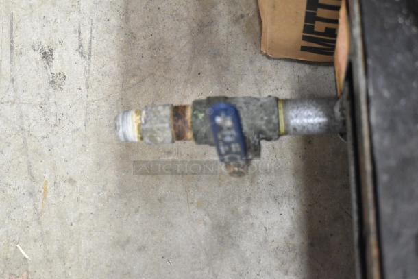 Rankin-Delux propane gas connecter detail, slightly rusted, attached to commercial countertop 2 burner range.