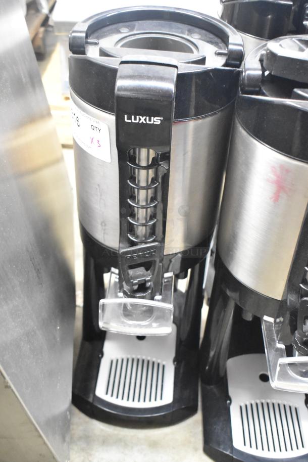 Fetco Luxus beverage dispenser, stainless steel, countertop model, includes 3 units, good condition, labeled "LUXUS."