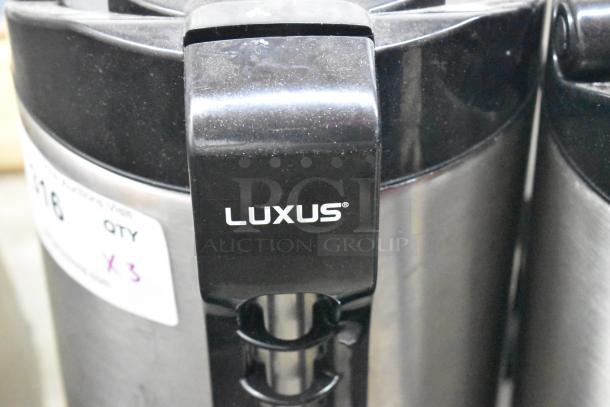 3 Fetco Luxus countertop beverage dispensers, stainless steel, labeled "Luxus." Includes quantity marker "x3," excellent condition.