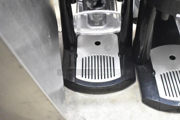 3 Fetco Luxus beverage holders with black and white drip trays, in clean condition, for countertop use.