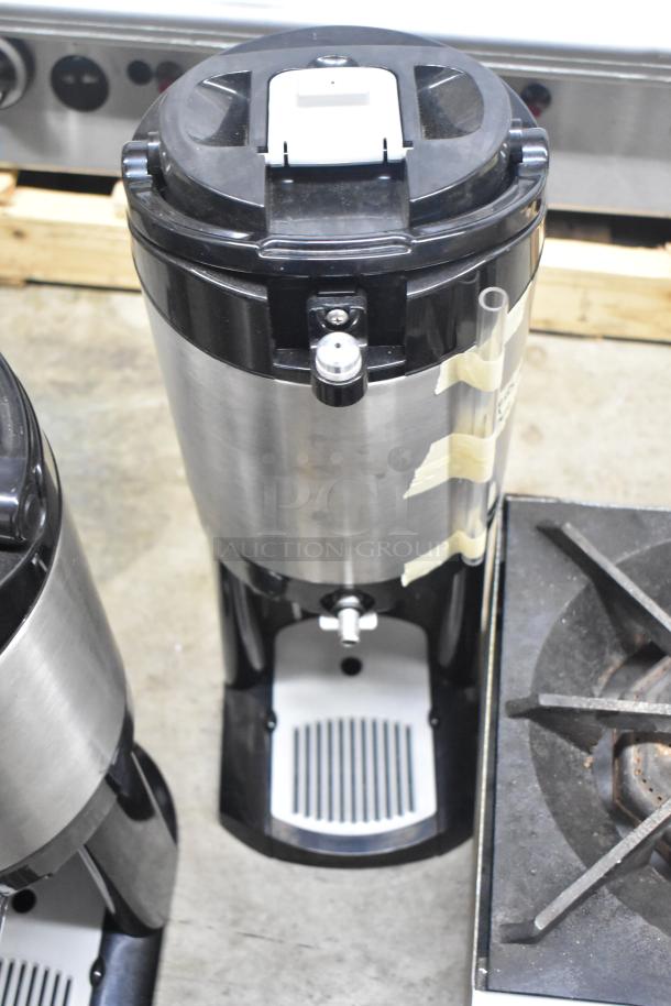 Three Fetco Luxus countertop beverage dispensers, stainless steel and black, with drip trays and tape markings, in used condition.
