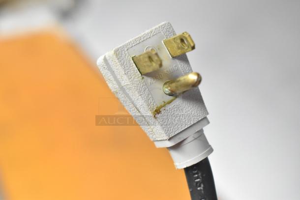 Close-up of a power plug for a True TSSU-48-18MB-HC commercial prep table. White textured casing, brass prongs.