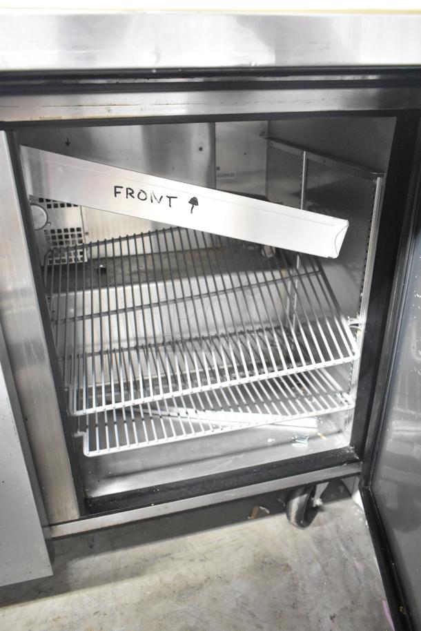 2016 True TSSU-48-18MB-HC commercial sandwich prep table interior with wire shelves, "FRONT" labeled guide, on casters.