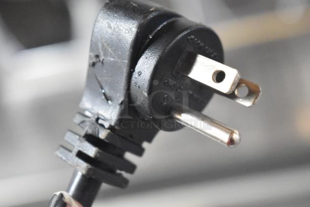 Close-up of a black power plug for the 2025 ServIt 423WDNFS1 Drawer Warmer, showing prongs and labeled voltage details.