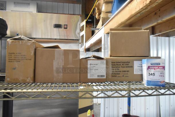 Six brand new "scratch and dent" boxes of medical supplies on a shelf, including PhysiciansCare and First Aid Only products with visible labels.