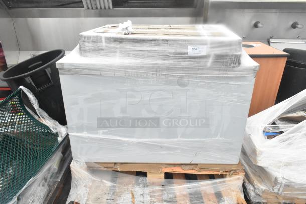 Plastic-wrapped table and wire shelves, brand new, scratch and dent condition, on a wooden pallet, with visible auction label.