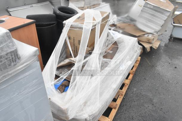 Four brand new scratch and dent items on a pallet, including a mop sink and work table, wrapped in plastic. Markings indicate NSF stainless steel.