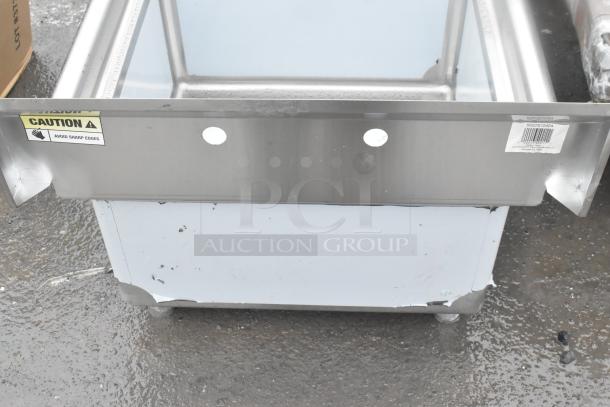 Stainless steel sink with visible dents and scratches. "Caution" sticker indicates sharp edges. Barcode label attached.