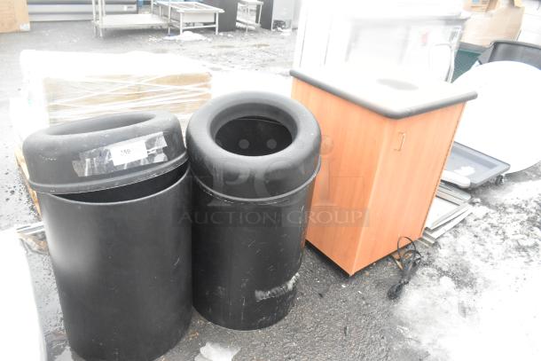 Three scratch and dent trash can shells: two black poly, one wood pattern. Tags visible, new condition.