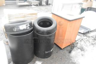 Three scratch and dent trash can shells: two black poly, one wood pattern. Tags visible, new condition.
