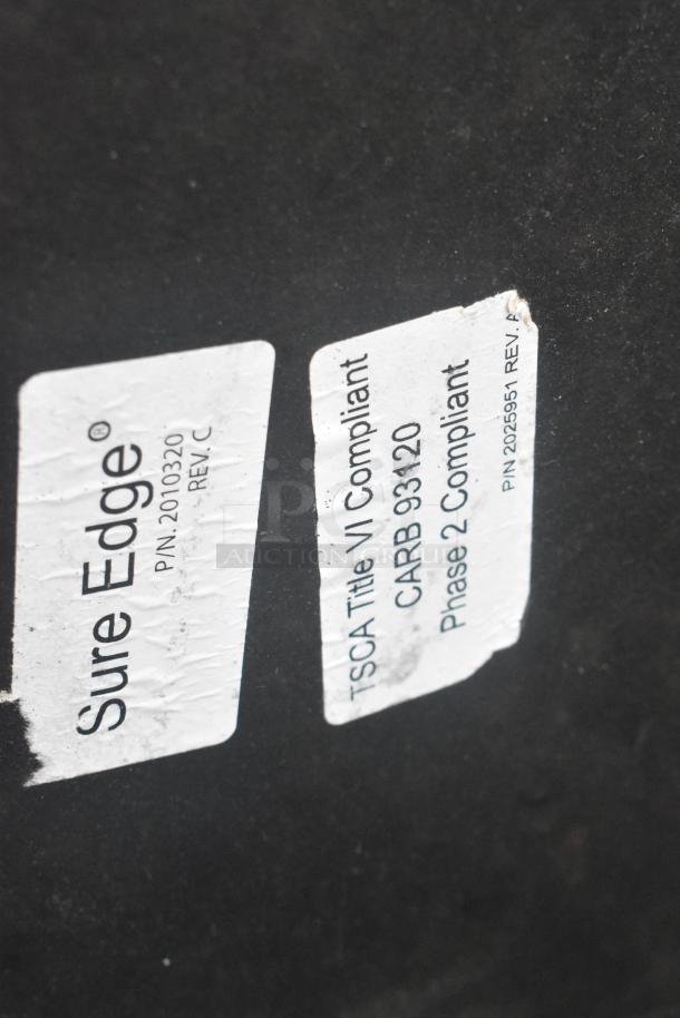 Round tabletop with Sure Edge label showing TSCA and CARB compliance, indicating safety standards.