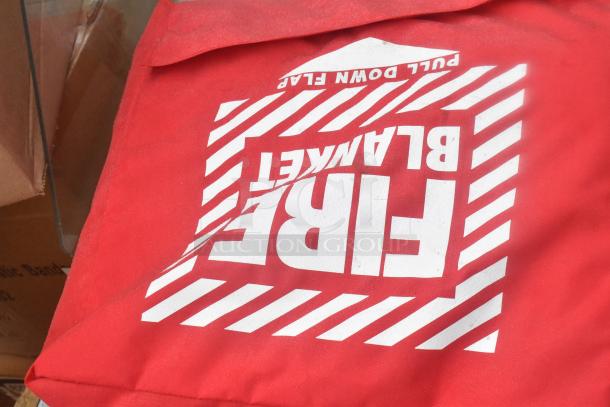 Red fire blanket with pull down flap text, included in a lot of 13 scratch and dent items like bandage wrap, eyewash station.