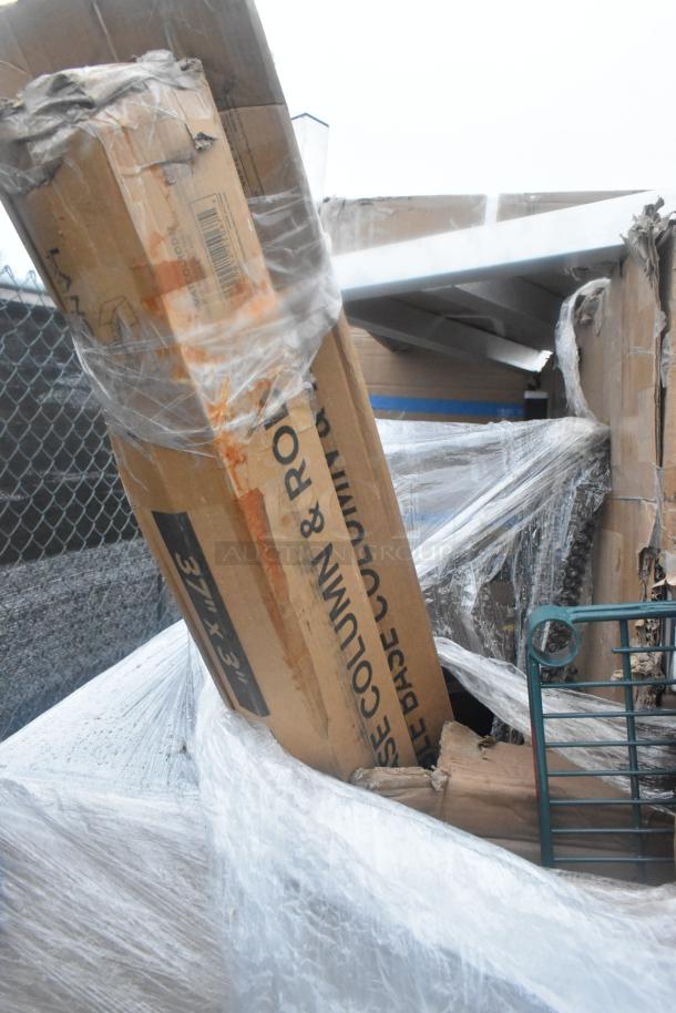 12 brand new scratch and dent items, including work tables and shelves, wrapped in plastic with visible labels.