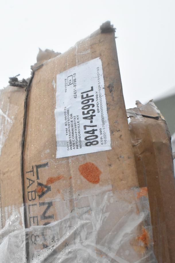 Cardboard packaging with label indicating item details. Visible scratches and dents. Contains work tables and shelving.