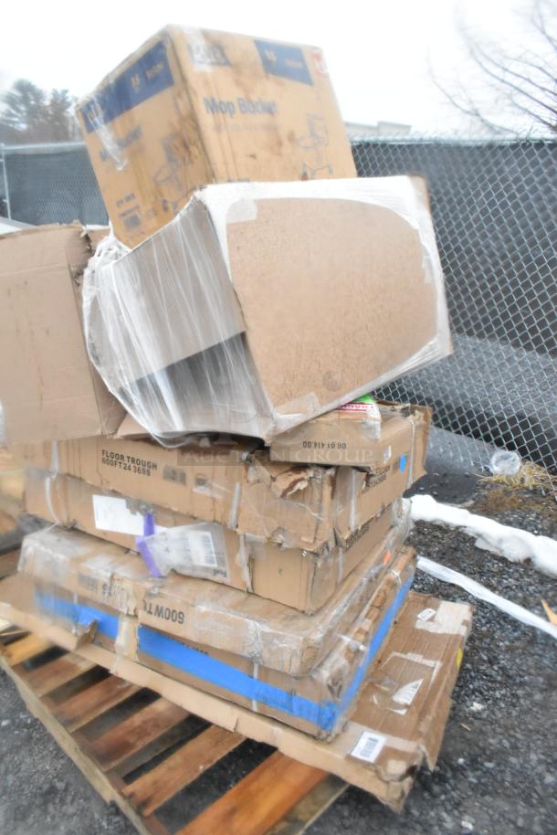 Stack of boxed items on a pallet including a new grease trap and floor troughs with visible scratch and dent damage.