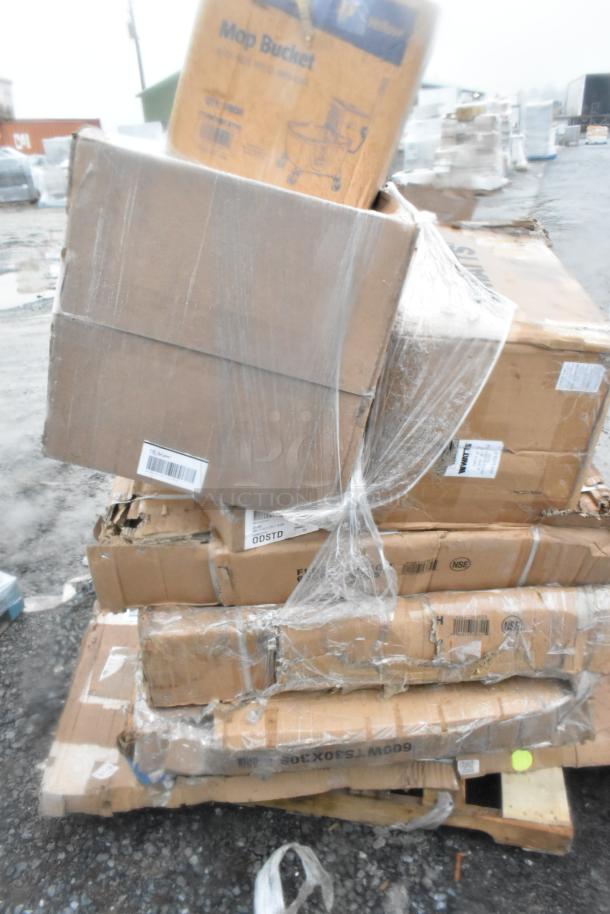 Stack of cardboard boxes containing 9 scratch and dent kitchen items, including grease trap and floor troughs. Items are shrink-wrapped and show visible shipping labels.