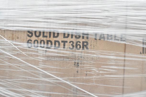 Cardboard box labeled "Solid Dish Table 600DDT36R" wrapped in plastic. Part of a new scratch and dent auction lot.