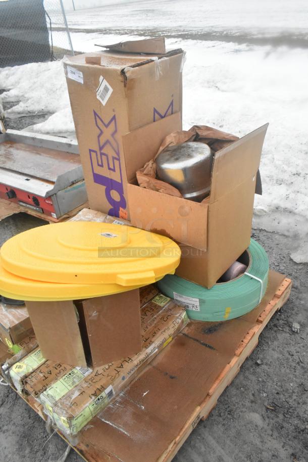 Assortment of new scratch and dent items on pallet including boxes, oven rack, storage solutions, and a yellow lid.