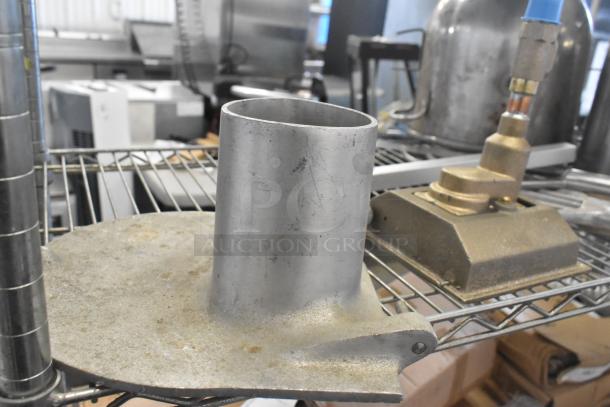 Alt text: Metal pelican head front piece and brass fixture on wire shelf in industrial setting, showing wear.