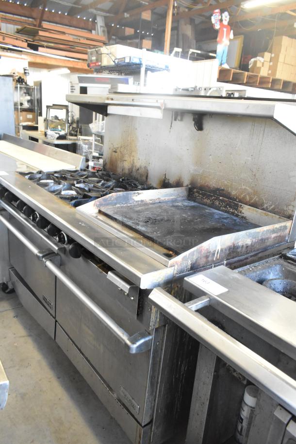 ThermaTek 6 burner range with flat top griddle and 2 ovens, gas powered, commercial use, visible wear, stainless steel.