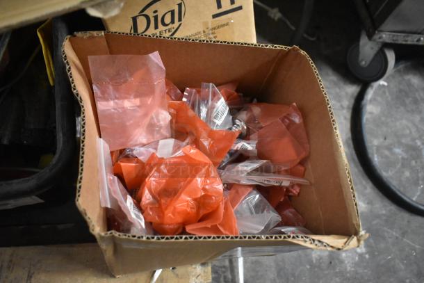 Box of mixed items including hardware in red and clear plastic bags, featuring various components and parts.