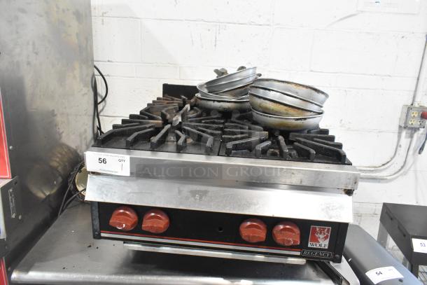 Wolf commercial countertop gas 4-burner range, used condition, red knobs, model label visible, stacked pans on top.