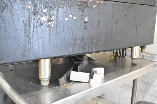 Wolf Commercial Countertop Gas 4 Burner Range with visible wear, stored on metal stand, includes detached control knobs.