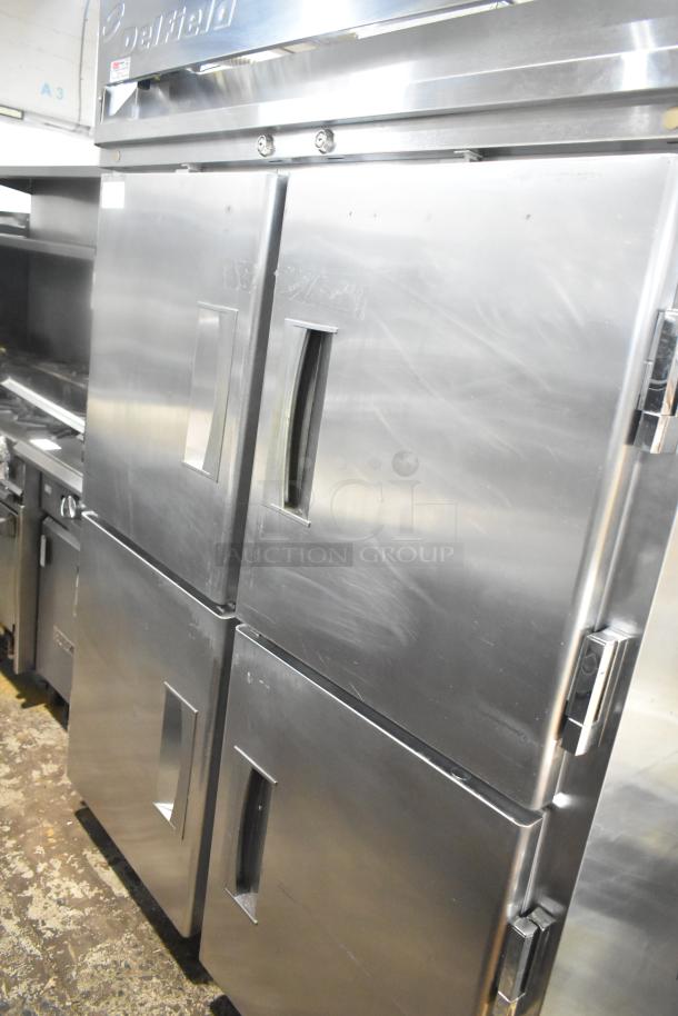 Delfield commercial cooler with four half-size doors on casters, stainless steel, pass-through design, good condition.