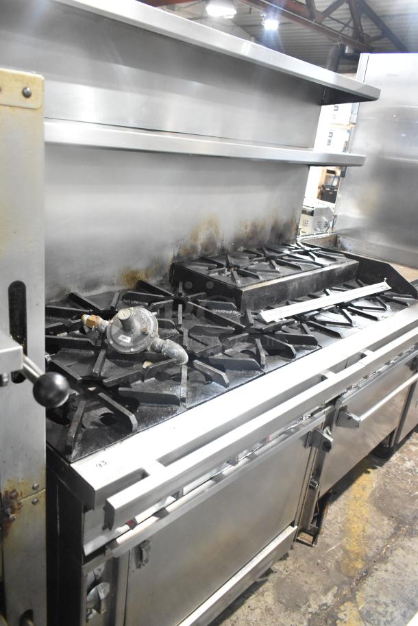 Commercial gas-powered 12-burner range with two ovens, over shelf, and backsplash on commercial casters. Used condition.