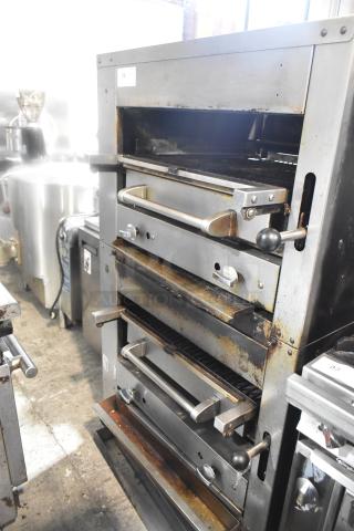 Commercial gas-powered vertical upright broiler on casters, stainless steel, used condition, multiple grilling levels.