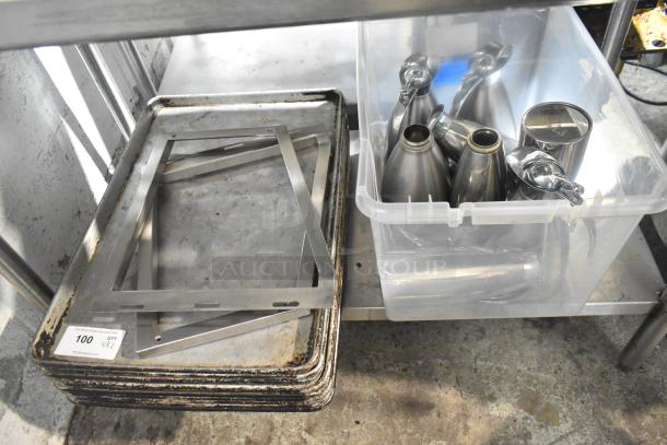Lot of metal baking pans with rust and plastic bin holding stainless steel pots and dispensers on industrial shelf.