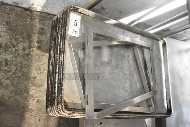 Lot of various metal baking pans with visible wear, stacked with a metal frame. Label: "100 QTY 072". Suitable for bulk sale.