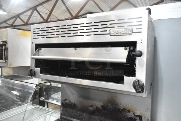 Imperial gas-powered 6-burner range with oven and salamander cheese melter, used condition, visible Imperial logo.