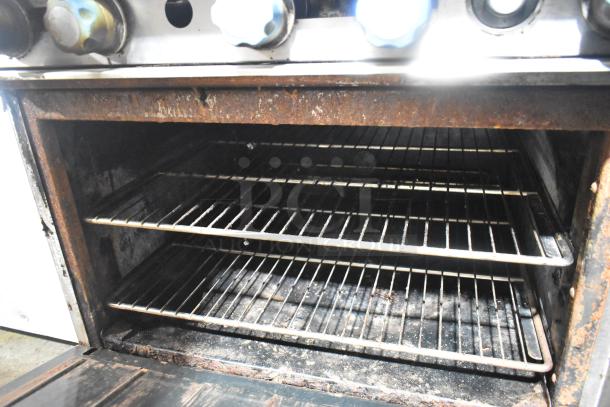 Imperial Commercial 6-Burner Gas Range with Salamander Cheese Melter and Oven, showing interior with racks; visible wear.