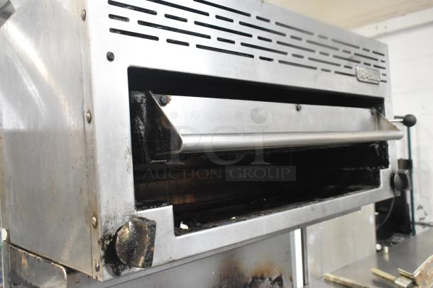 Imperial Commercial gas-powered range with 6 burners, salamander cheese melter, and oven. Visible signs of wear.