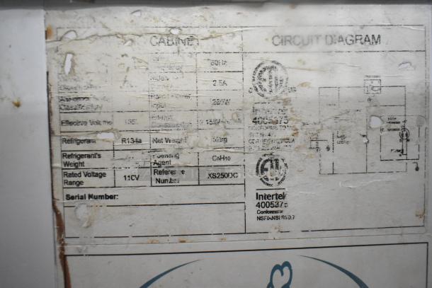 Commercial ice cream dipping cabinet label showing 115 volts, 1 phase, R134a refrigerant, and model XS250DC. Worn condition.